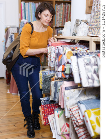 Woman choosing textiles in shop Woman choosing textiles in shop 111428715