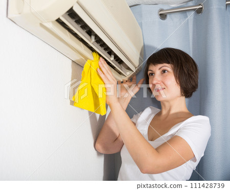 Woman dusting air conditioning Woman dusting air conditioning 111428739