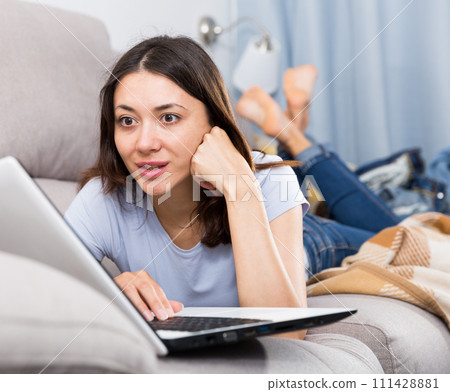 Young woman student resting with laptop on sofa at home Young woman student resting with laptop on sofa at home 111428881