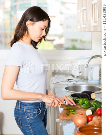 Young girl housewife cutting vegetables at home kitchen 111428999