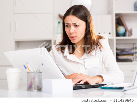 Tired young girl manager with laptop and documents working at office 111429646