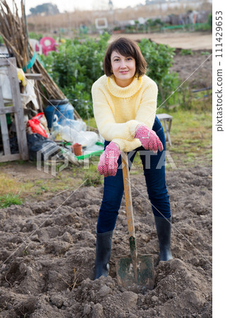 Girl in a yellow sweater digs beds with a shovel Girl in a yellow sweater digs beds with a shovel 111429653