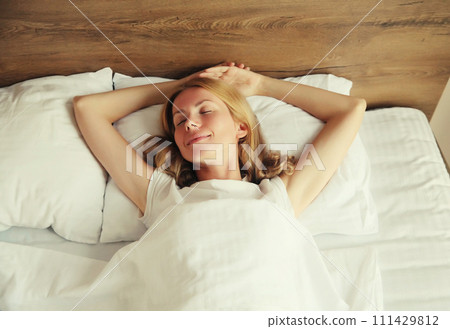 Young woman sleeping lying in bed on soft pillow in bedroom at home Young woman sleeping lying in bed on soft pillow in bedroom at home 111429812