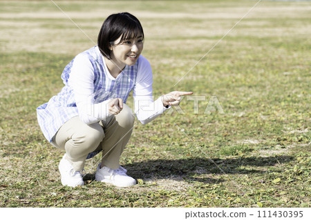 戶外育兒期間，女保育員在公園草地上玩耍 111430395
