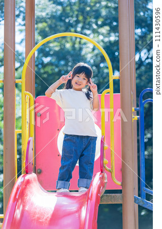 Girl posing on a slide in the park Girl posing on a slide in the park 111430596