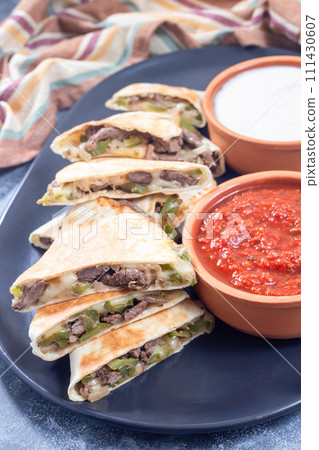 Fajita quesadilla with pieces of beef steak, green bell pepper, onion and cheese, on plate Fajita quesadilla with pieces of beef steak, green bell pepper, onion and cheese, on plate 111430607