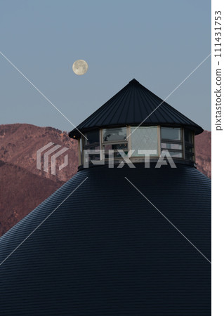 In the brightened sky, the moon, whose age is 14.6, sets behind the triangular roof of the roadside station. In the brightened sky, the moon, whose age is 14.6, sets behind the triangular roof of the roadside station. 111431753