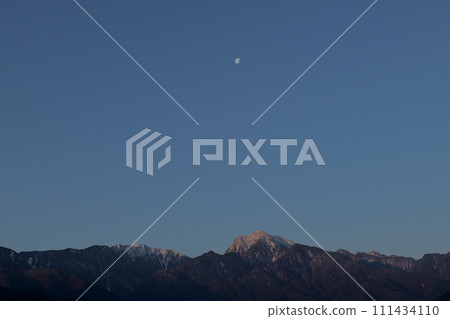 The dawn sky, the Ariake moon setting over the mountain range of Mt. Kaikomagatake in the Southern Alps The dawn sky, the Ariake moon setting over the mountain range of Mt. Kaikomagatake in the Southern Alps 111434110