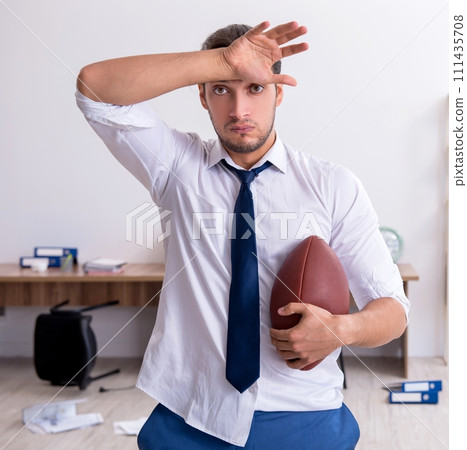 Young male employee throwing rugby ball in the office 111435708