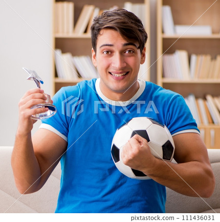 Man watching football at home sitting in couch Man watching football at home sitting in couch 111436031