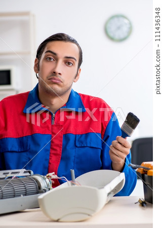 Young repairman repairing air-conditioner at warranty center 111436348