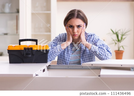 Young beautiful woman assembling furniture at home Young beautiful woman assembling furniture at home 111436496