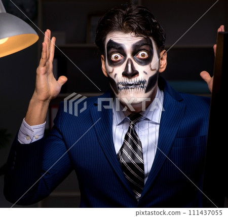 The businessman with scary face mask working late in office 111437055