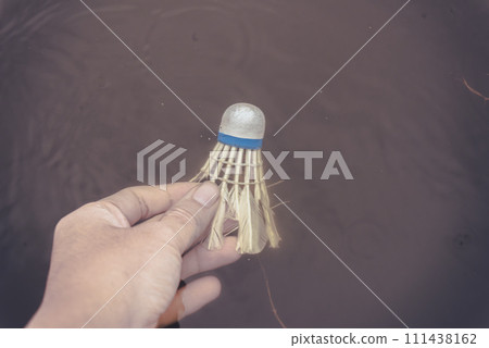 A hand dipped a broken racket ball into the water 111438162