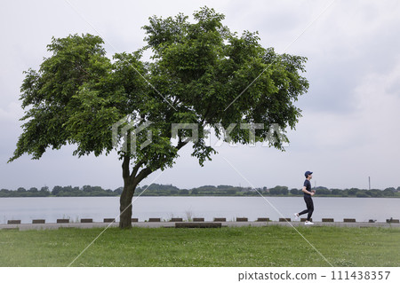 A man jogging in a lakeside park 111438357