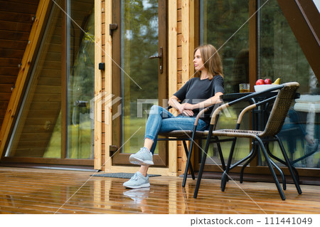 Cute woman enjoys fresh air after the rain in forest cabin 111441049