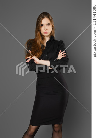 Serious woman in black blouse and skirt with folded arms Serious woman in black blouse and skirt with folded arms 111441096