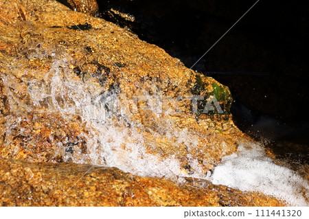Splashes of clear stream flowing down the rock surface Splashes of clear stream flowing down the rock surface 111441320