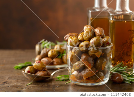 Spicy olives and bottles of olive oil on a wooden table. Spicy olives and bottles of olive oil on a wooden table. 111442408