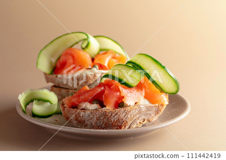 Sandwiches with smoked trout, cream cheese, fresh cucumber and capers. 111442419
