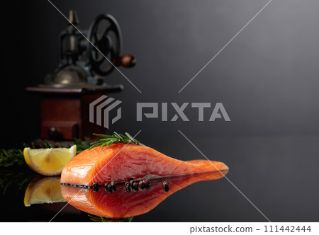 Salmon with rosemary, lemon, and peppercorn on a dark background. Salmon with rosemary, lemon, and peppercorn on a dark background. 111442444