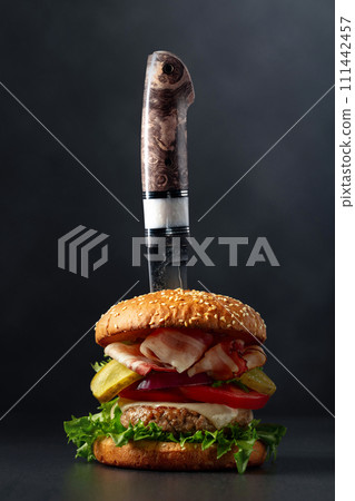 Fresh tasty burger with knife on a black background. Fresh tasty burger with knife on a black background. 111442457