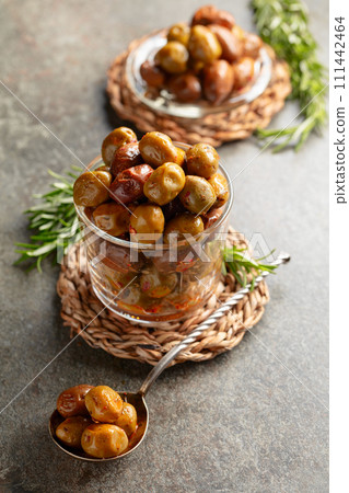Spicy olives in a glass bowl on a stone table. 111442464