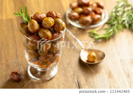 Spicy olives and rosemary twigs on a wooden table. 111442465