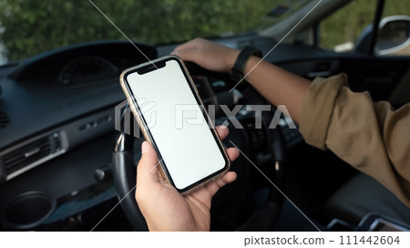 Cropped shot of man sitting behind wheel of a car and using smartphone. Closeup view 111442604