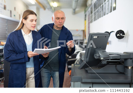 Service engineer conducts training on work on copiers of an office worker Service engineer conducts training on work on copiers of an office worker 111443192