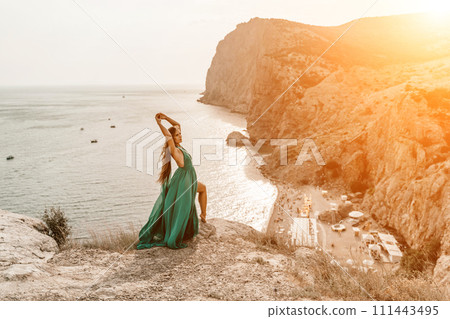 Woman sea trevel green dress. Side view a happy woman with long hair in a long mint dress posing on a beach with calm sea bokeh lights on sunny day. Girl on the nature on blue sky background. Woman sea trevel green dress. Side view a happy woman with long hair in a long mint dress posing on a beach with calm sea bokeh lights on sunny day. Girl on the nature on blue sky background. 111443495