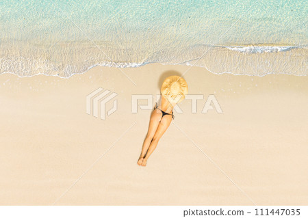 Top view of woman in bikini and straw hat lying and sunbathes on tropical Seychelles sea sand beach. Aerial, drone view Top view of woman in bikini and straw hat lying and sunbathes on tropical Seychelles sea sand beach. Aerial, drone view 111447035