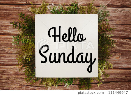 Hello Sunday text message with green leaves decoration on wooden background Hello Sunday text message with green leaves decoration on wooden background 111449947