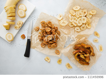 Chewy and crunchy banana slices and chips snack with raw banana and knife.Top view. 111450996