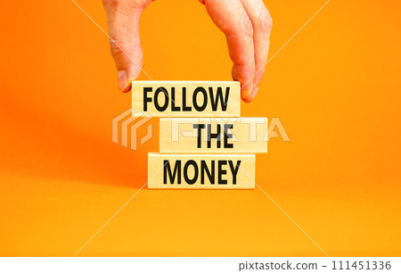 Follow the money symbol. Concept words Follow the money on beautiful wooden blocks. Beautiful orange table orange background. Businessman hand. Business and follow the money concept. Copy space. 111451336