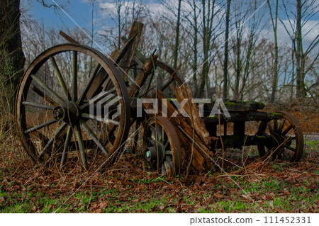 An old wooden wagon wheel is sitting in the grass 111452331