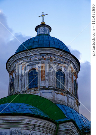 The image shows a weathered dome of a church with a cross on top, under a cloudy sky. The image shows a weathered dome of a church with a cross on top, under a cloudy sky. 111452680