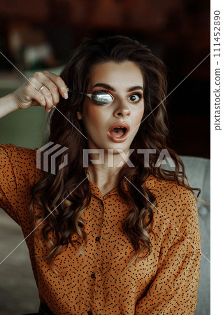 Playful woman covering eye with spoon. Playful woman covering eye with spoon. 111452890