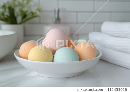A heap of multicolored bath bombs balls in a white bowl on a marble table in the bathroom 111453036