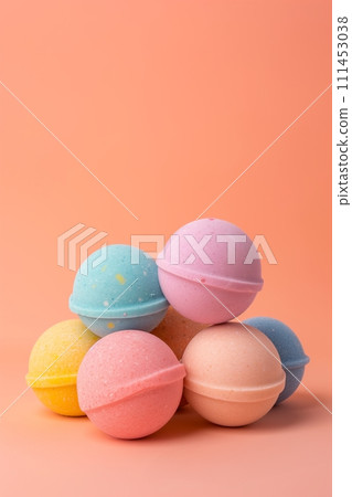 A heap of multicolored bath bombs balls on a peach background with space for text A heap of multicolored bath bombs balls on a peach background with space for text 111453038