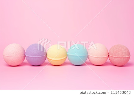 A variety of multicolored bath bombs balls on a pink background with space for text 111453043