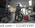 A man is fixing a bicycle in a garage 111453395