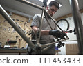 A man is working on a bicycle frame in a workshop 111453433