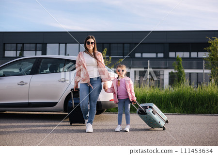 Adorable daughter with her mom go to airport with suitcases. Two girls goes to a trip. Little girl travel with mom. Adorable daughter with her mom go to airport with suitcases. Two girls goes to a trip. Little girl travel with mom. 111453634
