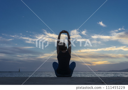 Silhouette of Serenity: Yoga at Sunset on the Tranquil Shoreline 111455229