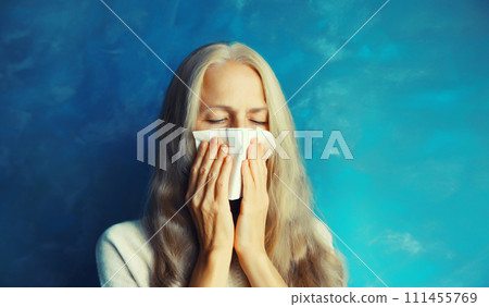 Sick exhausted middle-aged woman sneezing blow nose using tissue at home 111455769