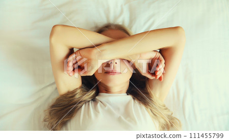 Tired sleepy woman wakes up lying on the bed on pillow in bedroom at home 111455799