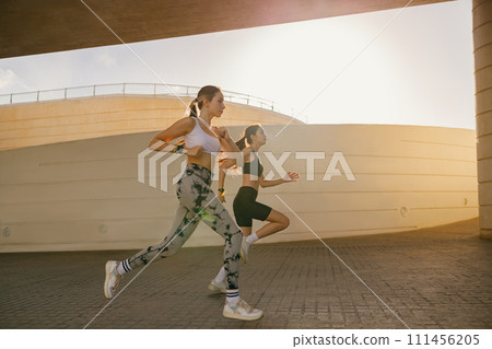 Young sporty women in sportswear are running on modern buildings background. Active lifestyle concept Young sporty women in sportswear are running on modern buildings background. Active lifestyle concept 111456205