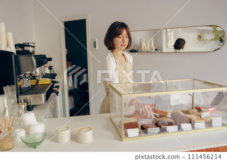 Female waitress's hand puts the piece of cupcake on the table at a cafe standing behind bar counter Female waitress's hand puts the piece of cupcake on the table at a cafe standing behind bar counter 111456214