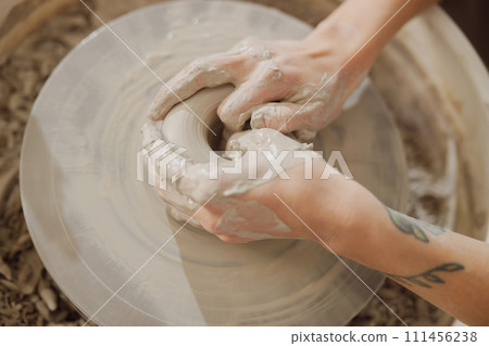 Close up of artisan's hands shaping clay bowl in pottery studio. Pottery art and creativity Close up of artisan's hands shaping clay bowl in pottery studio. Pottery art and creativity 111456238